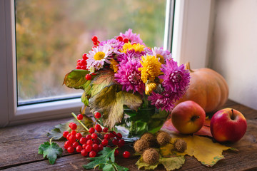 multicolored autumn chrysanthemum flowers in a glass vase on a wooden background.