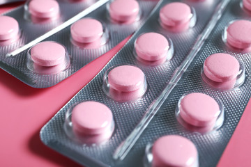 Blisters with pills on color background, closeup