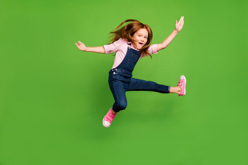 Full length photo of cheerful funny pretty little schoolchild jumping high fighting exercises...