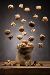 walnuts jumping out of the jute bag on wooden table