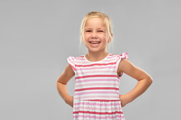 childhood and people concept - smiling little girl in striped dress over grey background