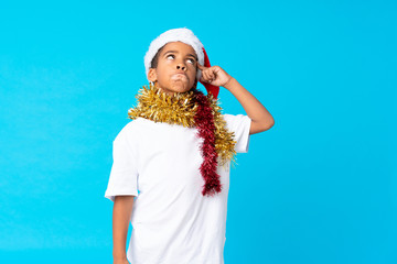 African American boy with christmas hat having doubts and with confuse face expression