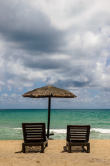 The beach chairs on sandy beach with cloudy blue sky and sun in the summer