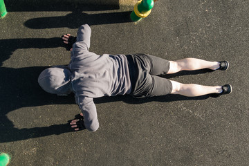 man in sweatshirt with a hood does push-ups, top view