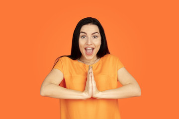 Obraz premium Caucasian young woman's portrait on orange studio background. Beautiful female brunette model in shirt. Concept of human emotions, facial expression, sales, ad. Copyspace. Smiling, laughting.