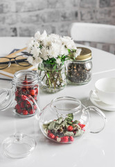 Kitchen table with herbal rosehip tea teapot, chrysanthemum bouquet, books. Cozy lazy home still life
