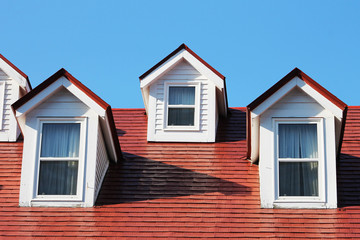 White dormers in a red roof, against a blue sky, old heritage building, downtown St. John's, Newfoundland.