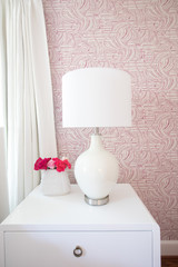 white bedside table with lamp and pink flowers - 299128741