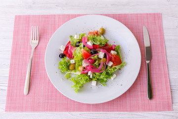 Tasty fresh Greek salad on white wooden table,