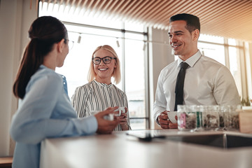 Smiling businesspeople talking together over coffee in their off