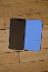 téléphone portable à coque bleue posée sur parquet