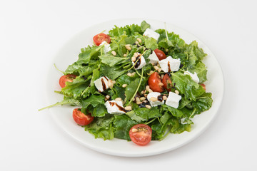 Green salad with vegetables: greens, arugula, tomato, cheese, pine nuts and sauce