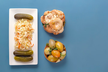 Fermented products pickles, tomatoes, mushrooms, cucumbers and sauerkraut on a blue background .Top view. Copy space