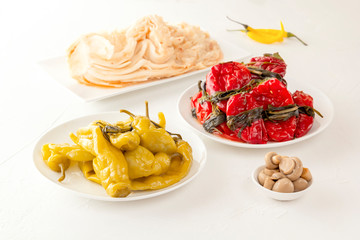Traditional Korean fermented food - red hot peppers with greens, yellow salted peppers and kimchi cabbage on a white table