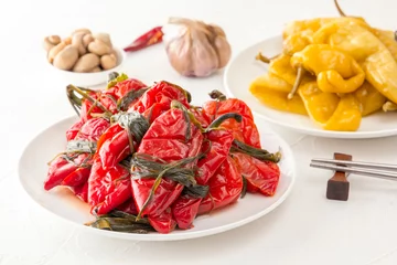Fotobehang Traditional Korean fermented food - red hot peppers with herbs on a white table. Close-up © alexey_arz
