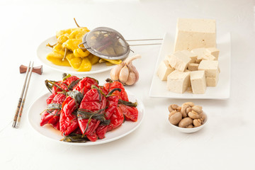 Traditional Korean fermented food - red hot peppers with herbs, yellow salted peppers and tofu bean curd on a white table
