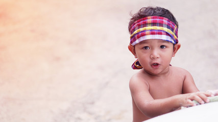 Cute Asian boys 2 year old don't wear shirts. He wear jeans He washed the car on holiday at home.The child who wrapped the loincloth on his head was sitting and resting.    