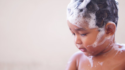 2-year-old Asian child takes a bath and bubbles into his eyes, using his hands to rub his eyes....