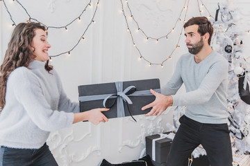 A shot of cheerful careless couple fighting for the new year box.