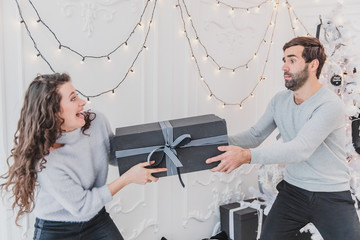 A shot of cheerful careless couple fighting for the new year box.
