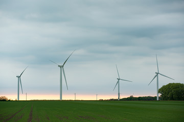 Wind turbines on the green field at cloudy day