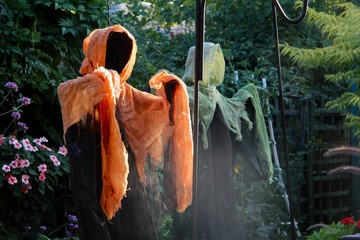 Spooky headless Halloween ghouls dressed in orange and mint green guard the midnight garden of good...