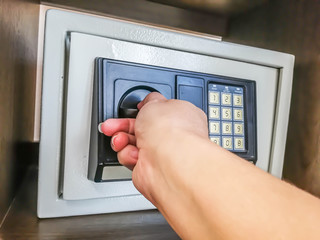 Closeup of woman 's hand unlock the safe box in wooden cupboard in hotel or hospital room.