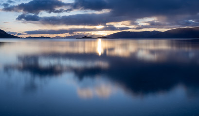 loch linnhe in the argyll region of the highlands of scotland during an autumn sunset showing golden light on the clouds and water and the islands of lismore and shuna
