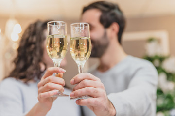 Toasting with champagne glasses against holiday lights and christmas tree.