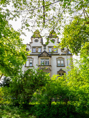 Beautiful decorated old building hidden behind green April tree branches in Trier, the oldest town of Germany