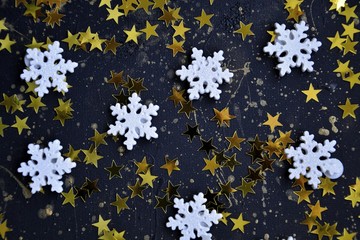 Dark background with scattered golden stars and snowflakes with space for text. Christmas, New Year.  confetti