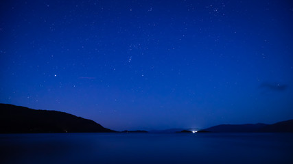 Fototapeta na wymiar a view of the stars on the shore of loch linnhe a sea loch in the argyll region of the highlands of scotland during a crystal clear night in autumn