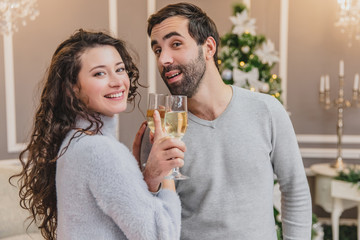 Close up portrait of a young couple in love on new year night, drinking brotherhood.