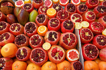 Group of sliced pomegranates and grapefruits displayed on fruit juice seller's counter. Front View.