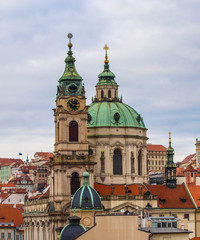 Fototapeta na wymiar St. Nicholas baroque church above houses roofs in Prague, Czech Republic