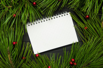 Fototapeta na wymiar Christmas gifts shopping planning. Notebook with christmas tree on the wooden background. New year goals or shopping list.