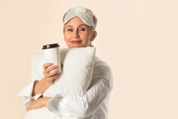 stylish beautiful aged woman with a short haircut with a pillow and a cup of coffee in her hands
