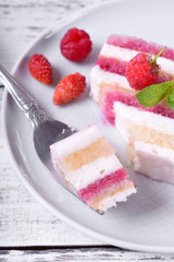 Piece of cake with many layers topped with fresh berries on a ceramic plate