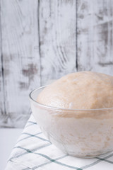 Yeast dough in a glass bowl ready to be formed into bakery products against white background
