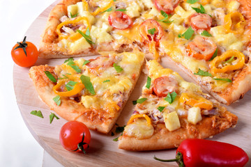 Pizza with chicken, cheese, tomatoes and bell peppers served on the round wooden board. Italian cuisine meal
