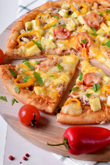 Pizza with chicken, cheese, tomatoes and bell peppers served on the round wooden board. Italian cuisine meal