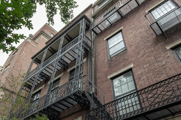 Fototapeta na wymiar Elaborate balcony railings on the face of old brick apartment buildings, view looking up, horizontal aspect
