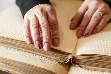 woman reading braille text on old book