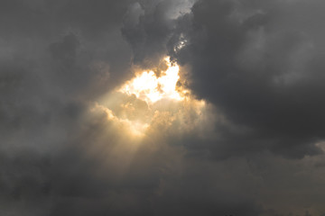 Beautiful gloden sun rays of light shining through the rain clouds in the sky, light from heaven, holy concept.