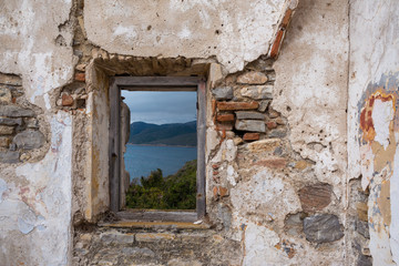 Fototapeta na wymiar Old window overlooking the sea and mountains of the natural park