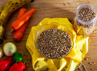 Small plate with raw lentils and some vegetables that accompany this flat once cooked