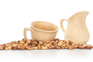 Lot of whole fresh brown bean vicia faba with ceramic cup and ceramic jug isolated on white background