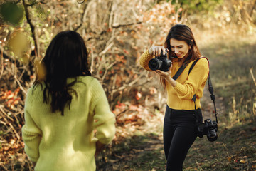 young woman photographer takes pictures of model in nature, the photographer in action