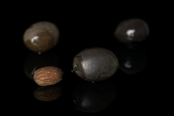 Group of three whole one piece of canned black olive with olive stone isolated on black glass