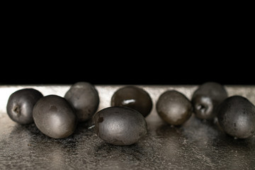 Lot of whole canned black olive on tray isolated on black glass
